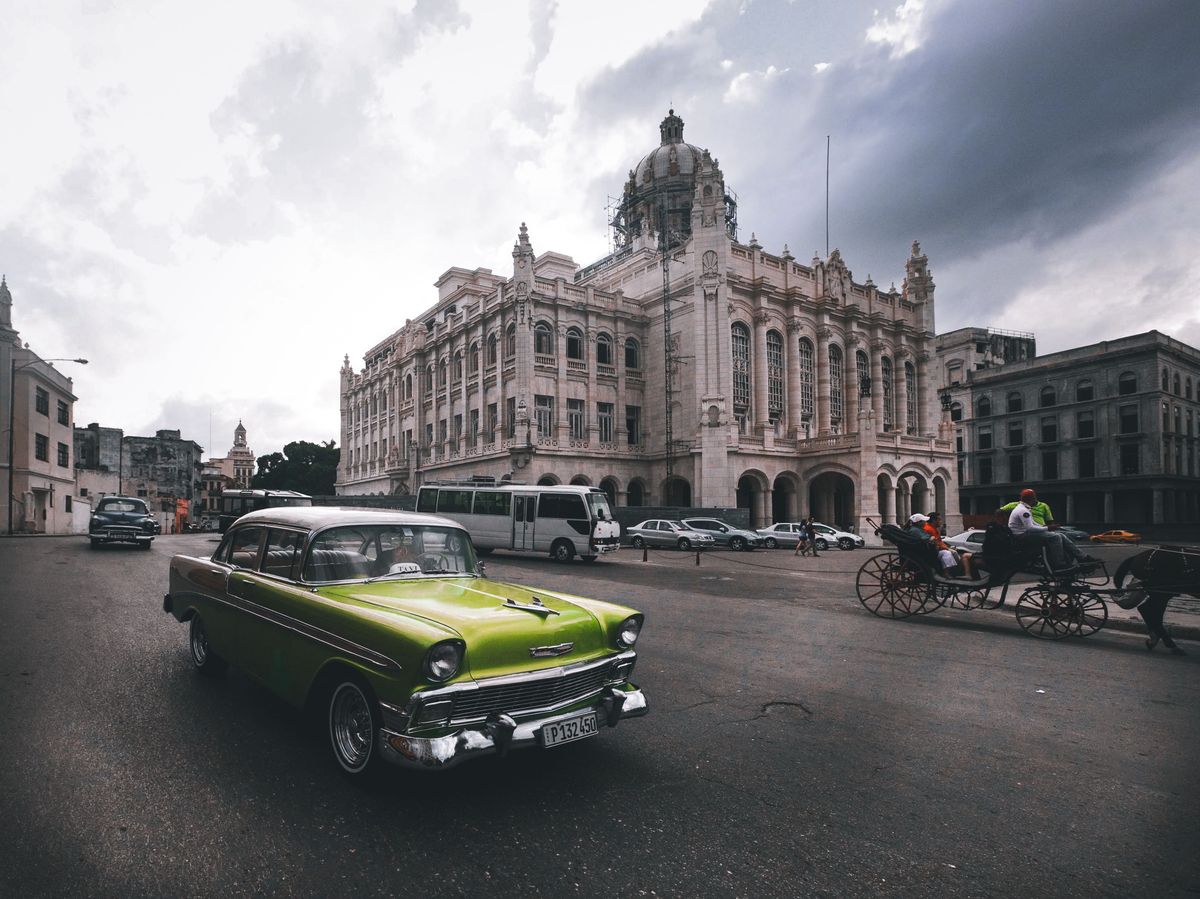 Klasický americký automobil projíždí kolem historické budovy v&nbsp;centru Havany na Kubě za ponurého oblačného dne.