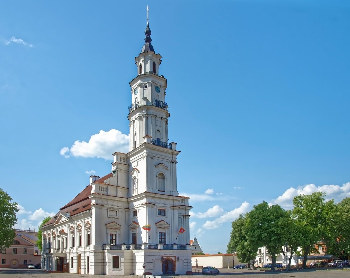 Radnice v&nbsp;Kaunasu s&nbsp;vysokou bílou věží na modré obloze s&nbsp;několika oblaky.