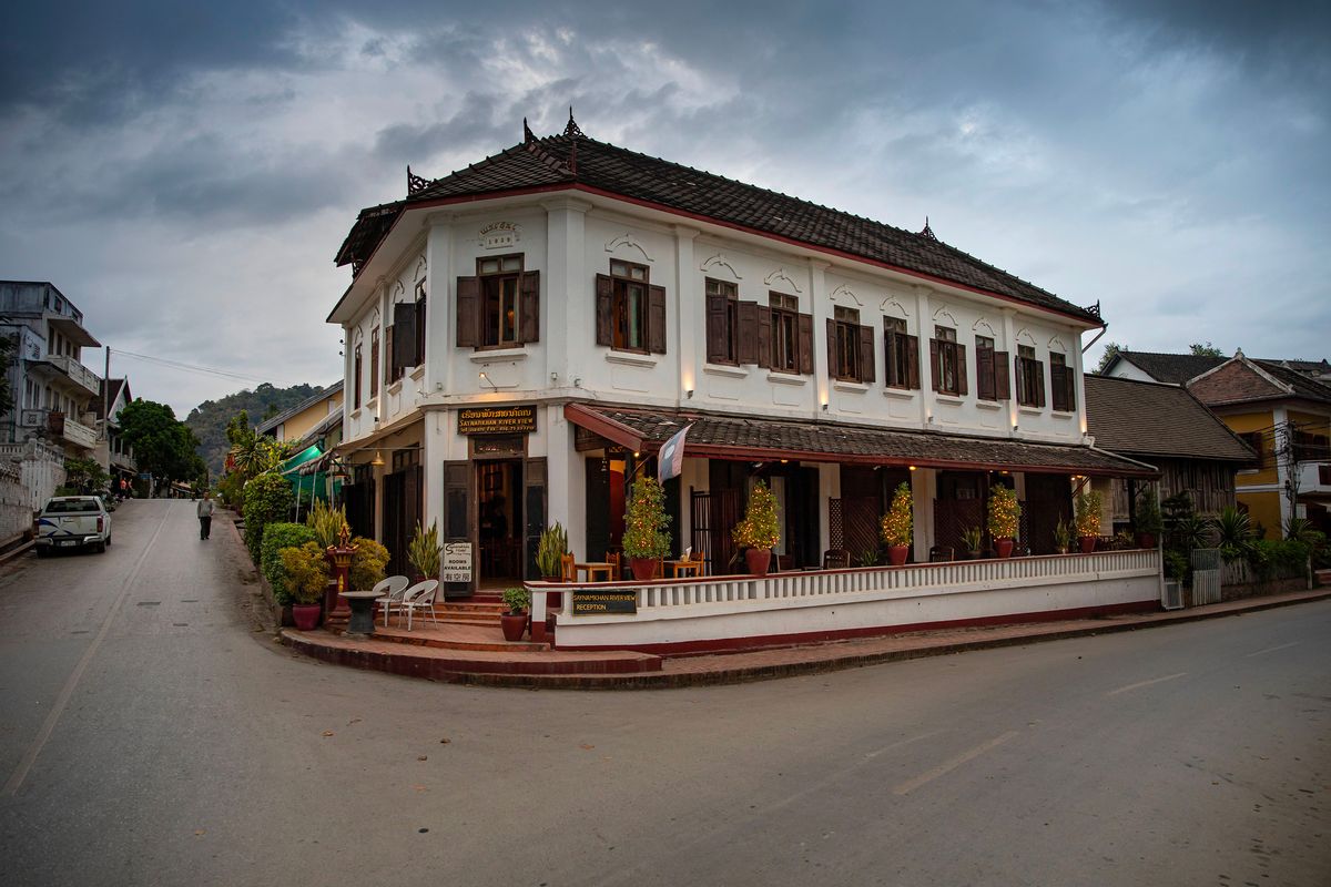 Koloniální budova v&nbsp;Luang Prabang s&nbsp;tradičními dřevěnými okenicemi a&nbsp;rustikálním vzhledem obklopená tropickou vegetací.