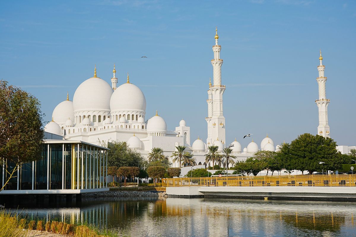 Velká mešita šejka Zayeda v Abú Dhabí se svými impozantními bílými kopulemi a minarety odráží v klidné vodní ploše.
