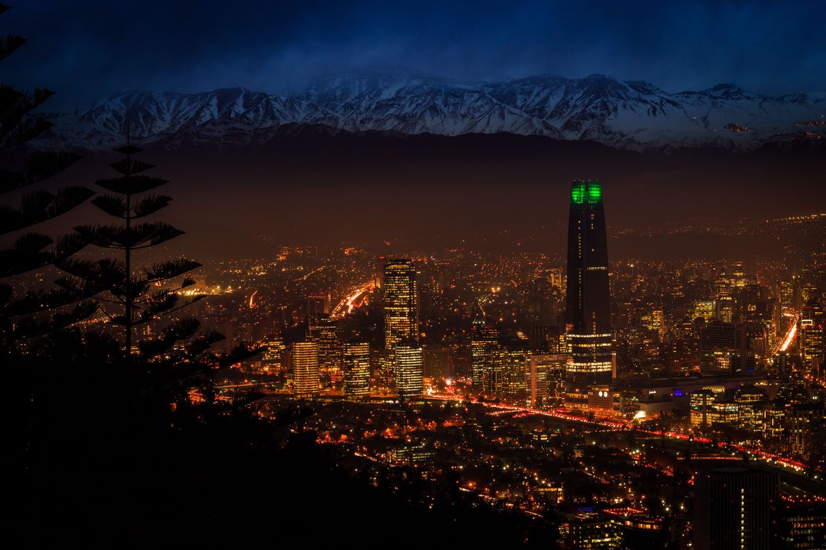 Noční panorama města Santiago s&nbsp;majestátním pohořím Andy v&nbsp;pozadí.