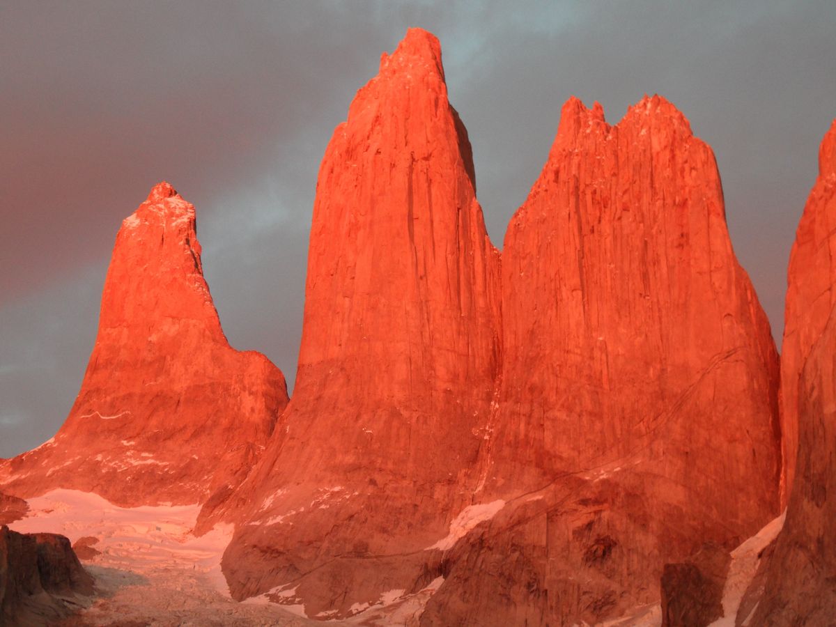 Tři majestátní žulové věže vykreslené slunečním západem v&nbsp;národním parku Torres del Paine v&nbsp;Chile.