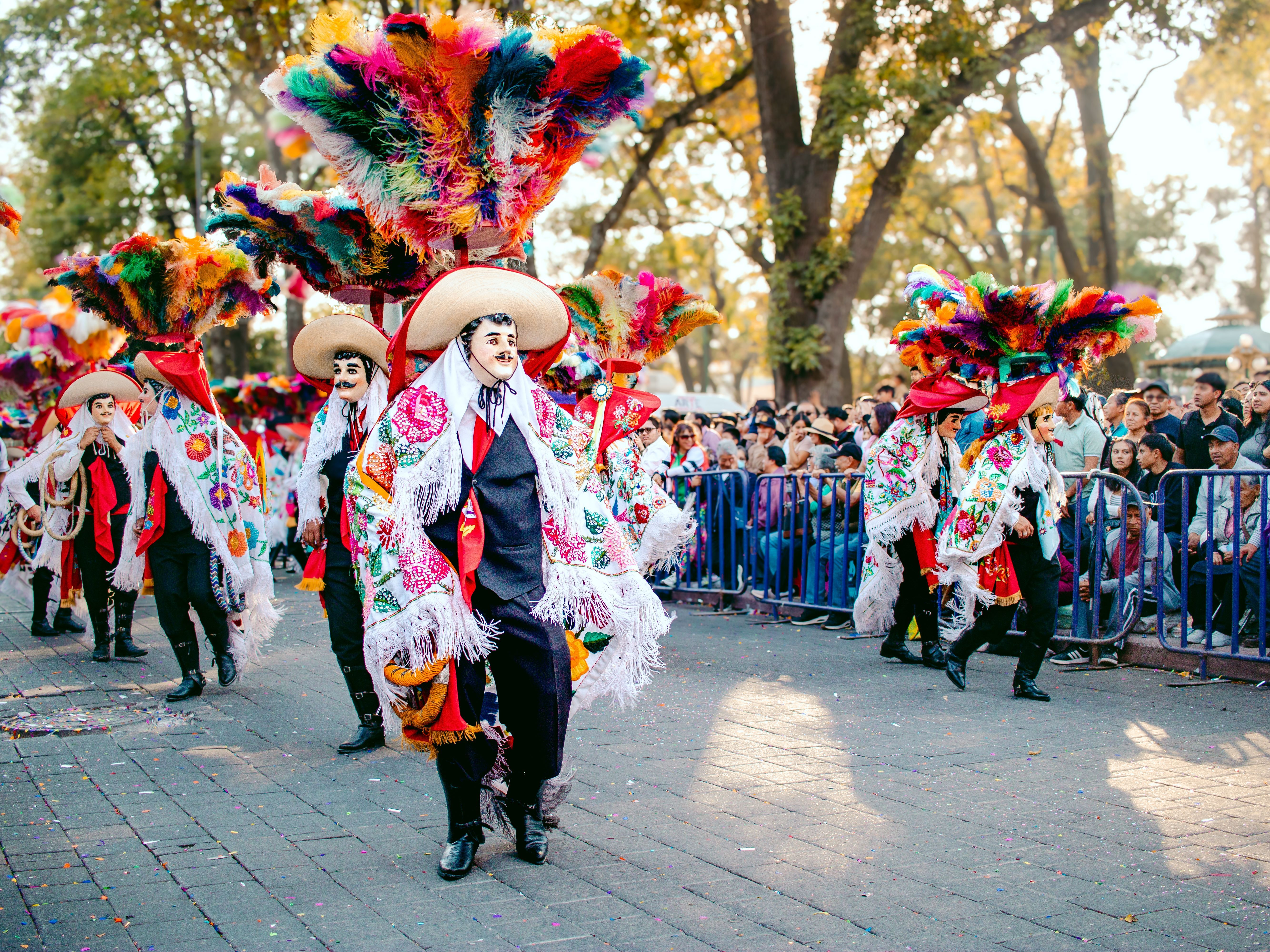 Účastníci tradičního průvodu v&nbsp;Mexiku oblečení v&nbsp;pestré kostýmy s&nbsp;velkými klobouky a&nbsp;maskami tančí ulicemi města během slavnosti Día de los Muertos.