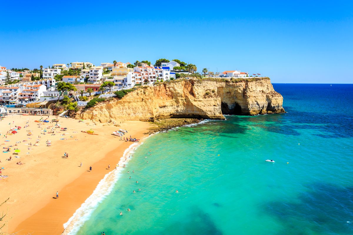 Pláž s&nbsp;jemným pískem obklopená útesy a&nbsp;malebnými bílými domy v&nbsp;letovisku Carvoeiro, Algarve.