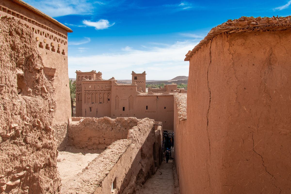 Hliněné zdi a tradiční stavby berberské vesnice Aït Ben Haddou se tyčí pod jasně modrým nebem v Maroku.