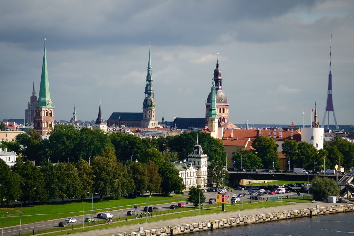 Pohled na historické centrum Rigy s&nbsp;výraznými kostelními věžemi a&nbsp;moderní televizní věží v&nbsp;pozadí.