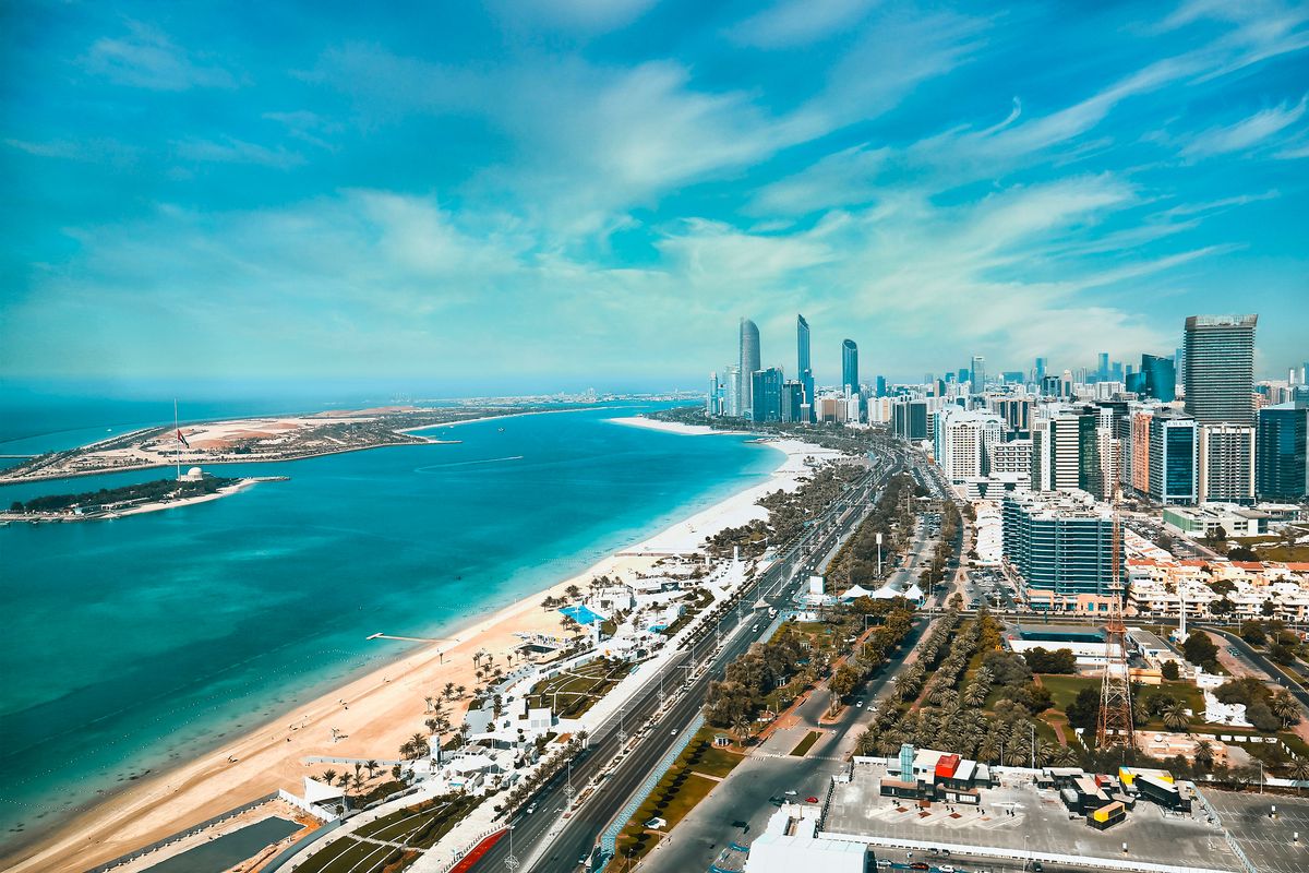 Pohled na pláž Corniche a moderní panorama Abu Dhabi s vysokými mrakodrapy a modrou hladinou Arabského zálivu.