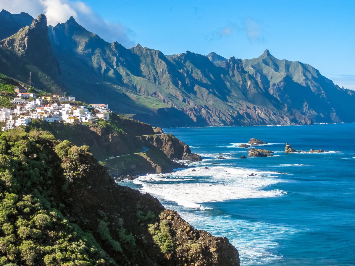 Pobřežní vesnice s bílými domy se rozkládá na útesu nad modrým Atlantickým oceánem poblíž pláže Benijo na Tenerife, Kanárské ostrovy.