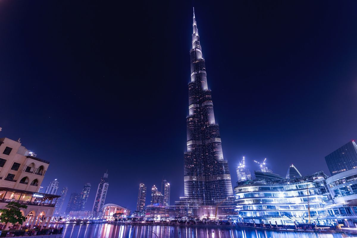 Burj Khalifa osvětlený v noci, obklopený dalšími mrakodrapy a moderní architekturou v Dubaji.