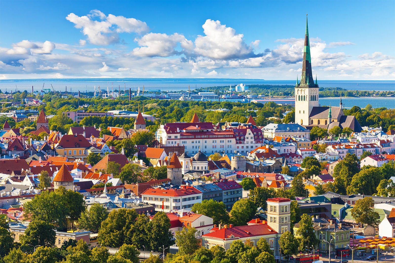 Panorama historického centra Tallinnu s&nbsp;výraznou věží kostela svatého Olafa a&nbsp;Baltským mořem v&nbsp;pozadí.
