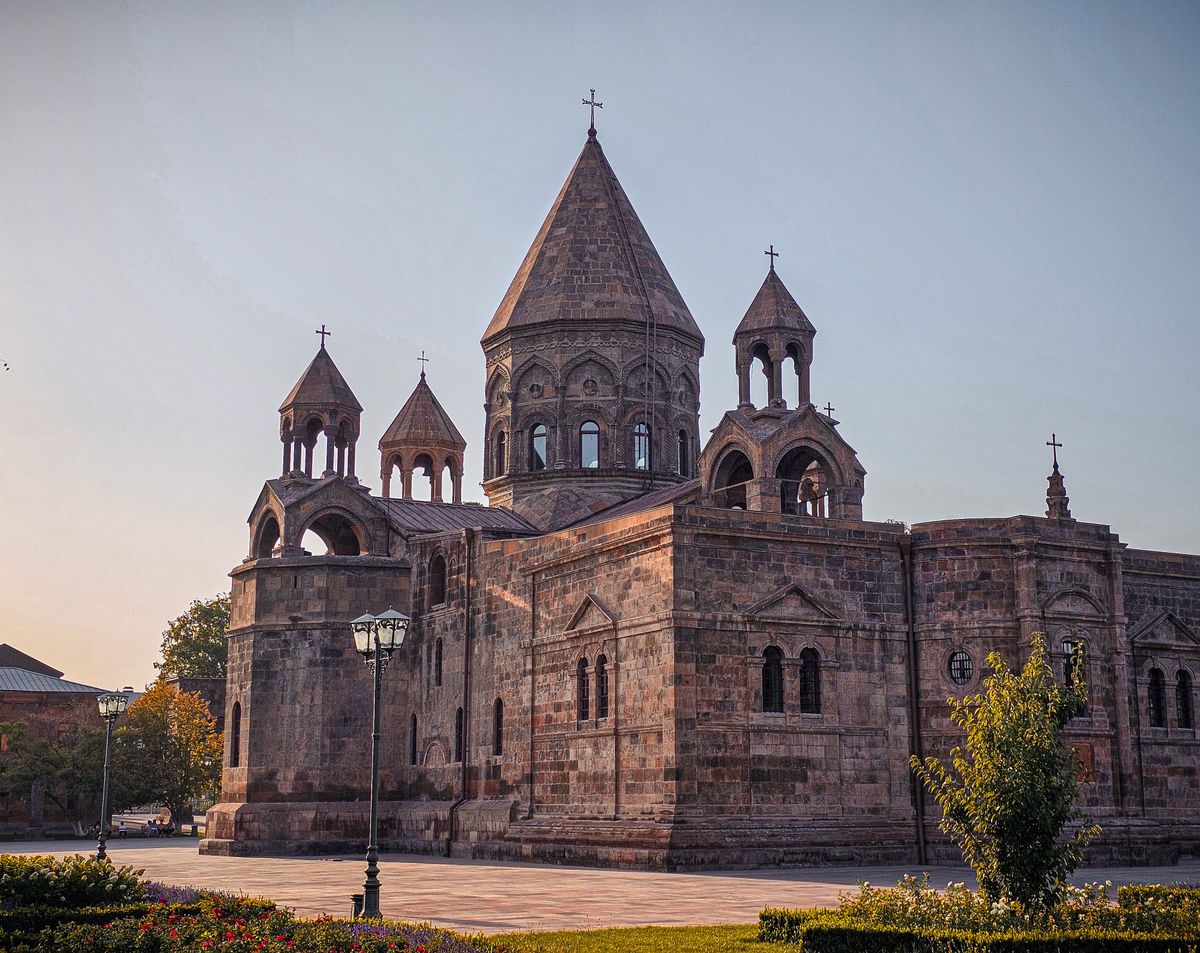 Katedrála Etchmiadzin, významná arménská katedrála, s krásnou architekturou a věžemi zalitými večerním světlem.