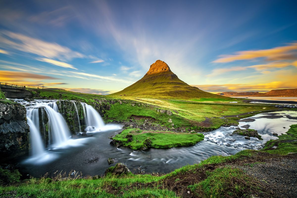Pohled na ikonickou horu Kirkjufell na Islandu s malebným vodopádem v popředí.