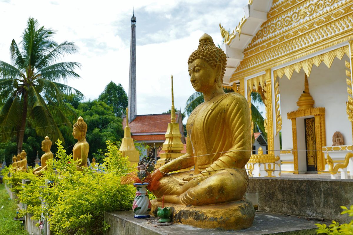 Zlatá socha Buddhy v chrámu na ostrově Ko Samui obklopená tropickou zahradou.