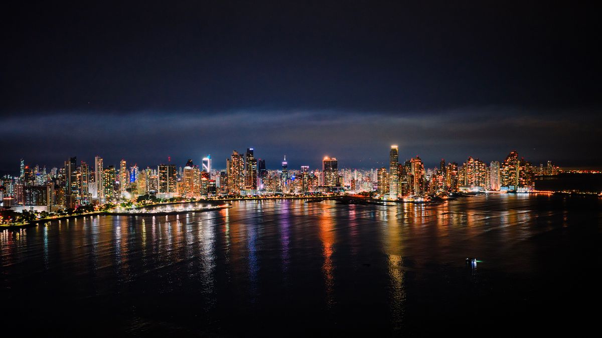 Noční panoráma Panama City s&nbsp;osvětlenými mrakodrapy odrážejícími se na hladině moře.