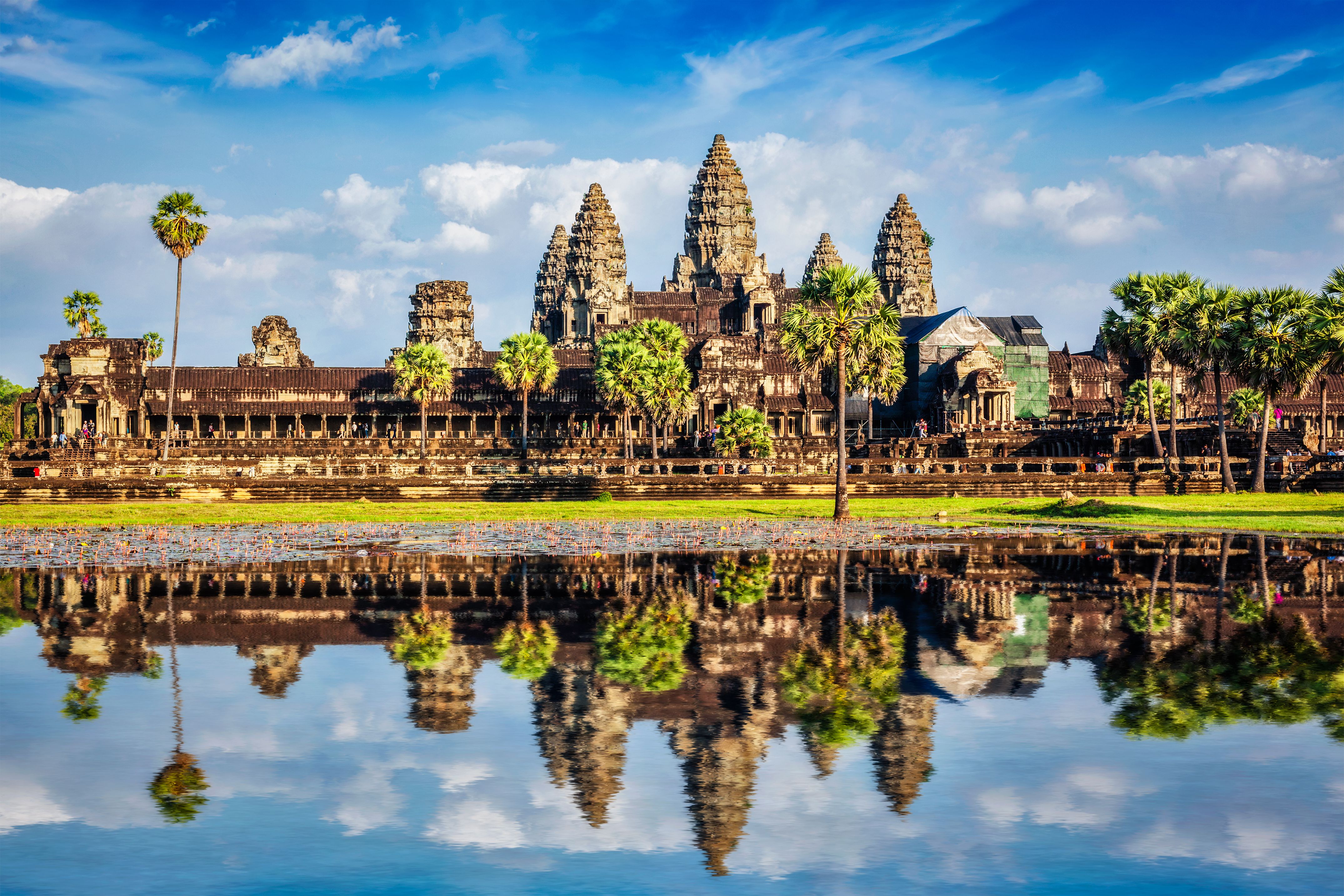 Chrámový komplex Angkor Wat v&nbsp;Kambodži je zrcadlený ve vodní hladině za slunečného dne.
