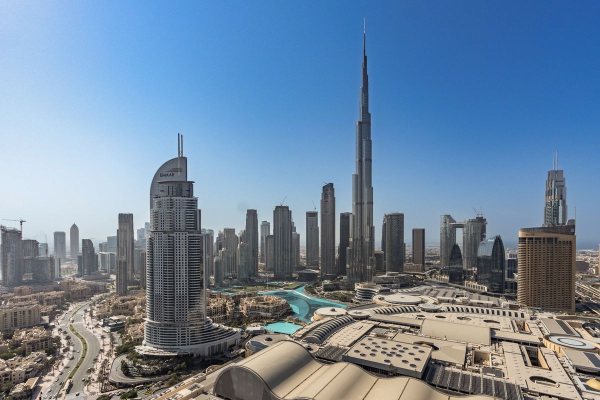 Pohled na ikonické panorama Dubaje s mrakodrapem Burdž Chalífa v popředí zářícím pod jasným modrým nebem.