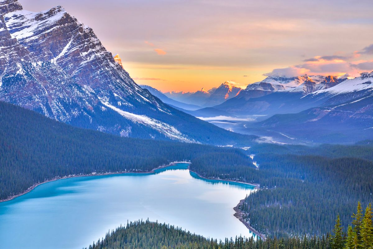 Úchvatný pohled na jezero Peyto obklopené zasněženými vrcholky Skalistých hor při západu slunce.
