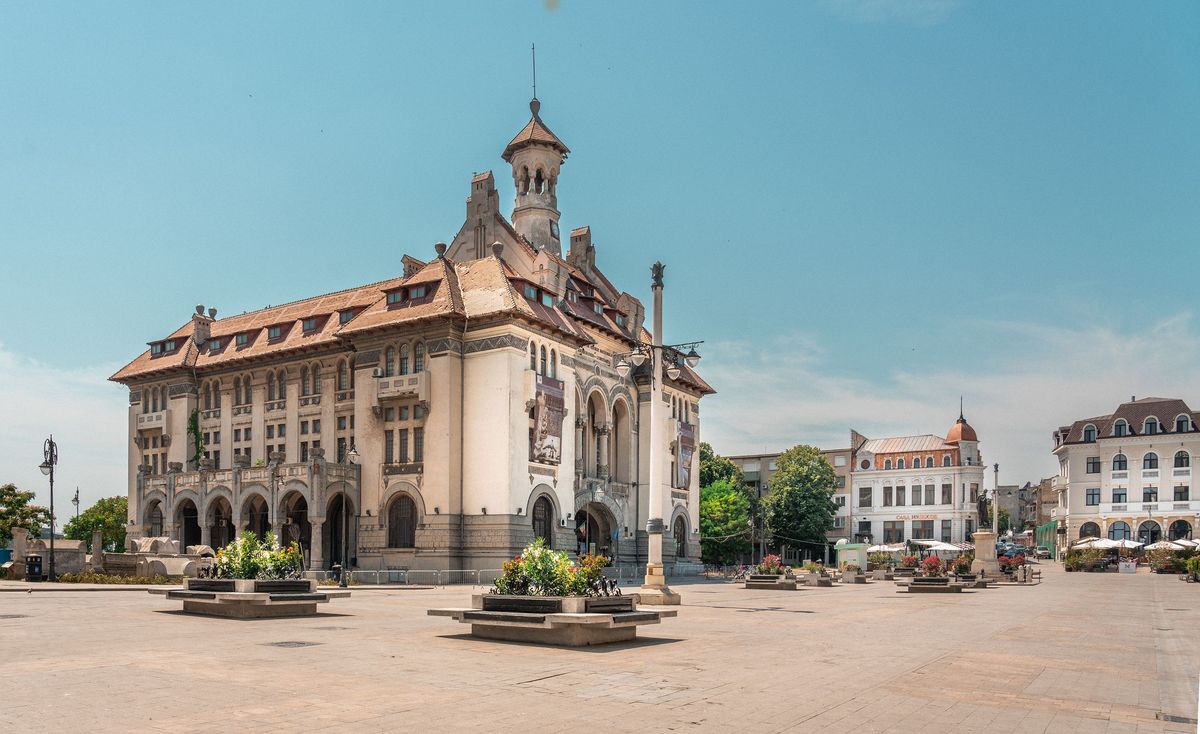 Historická budova v&nbsp;centru města Konstanca září pod jasně modrou oblohou a&nbsp;je obklopena květinovou výzdobou na náměstí před ní.