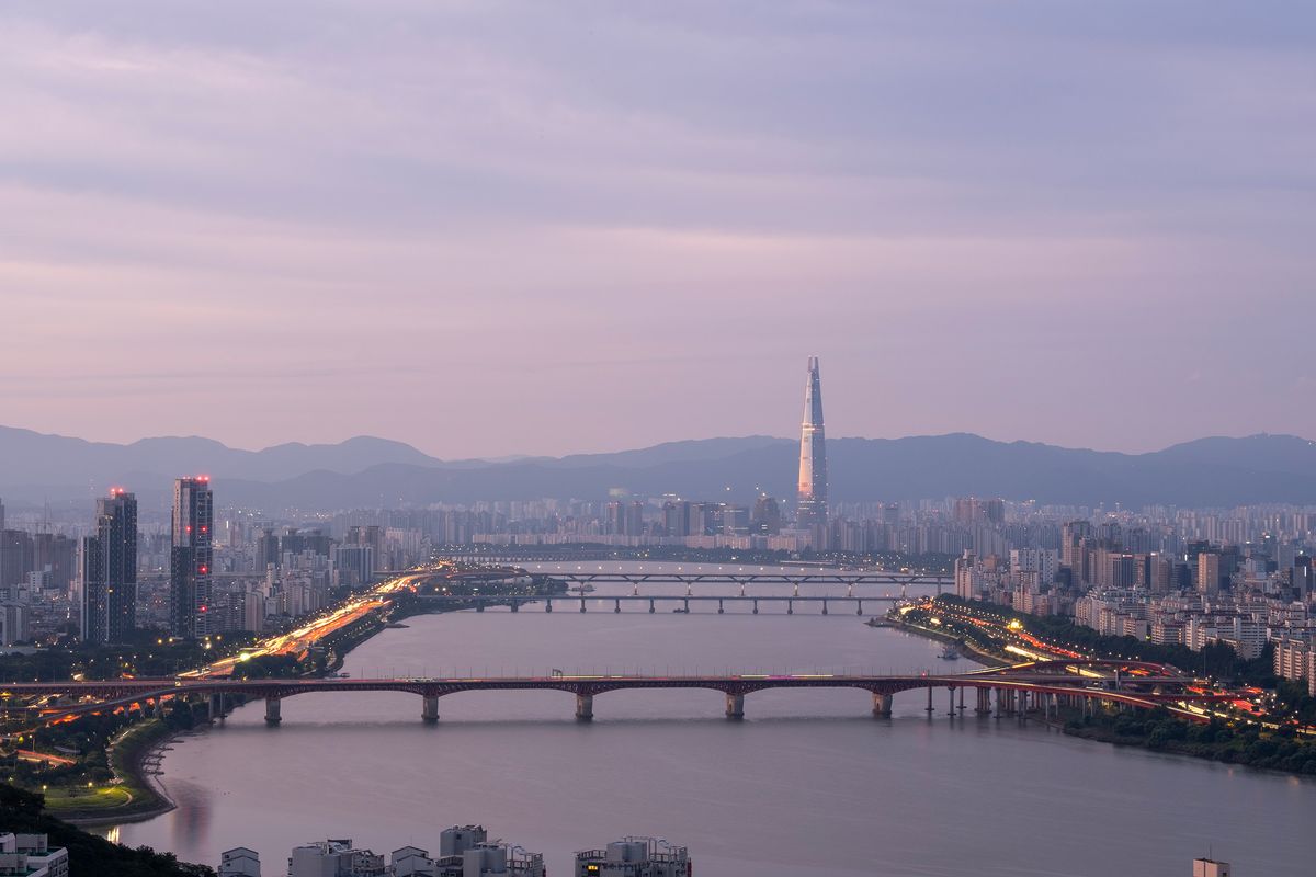 Panoramatický pohled na Soul s&nbsp;řekou Han a&nbsp;věží Lotte World Tower na pozadí soumraku.