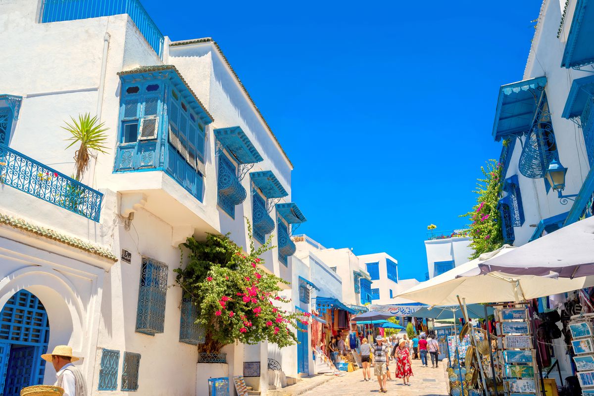 Malebná ulice v modro-bílé čtvrti Sidi Bou Said v Tunisku, s tradiční architekturou a květinovou výzdobou.