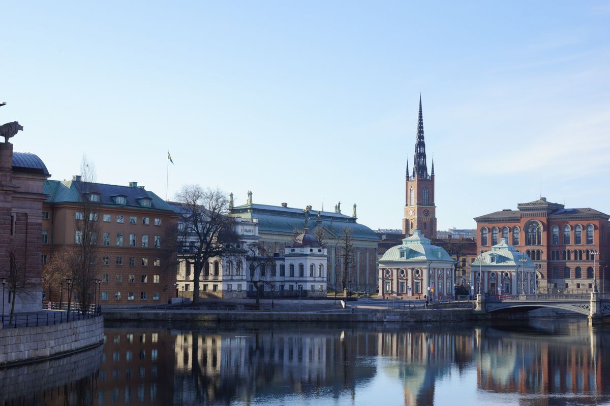 Historické budovy a kostel Riddarholmskyrkan se odrážejí na hladině vody ve městě Stockholm.