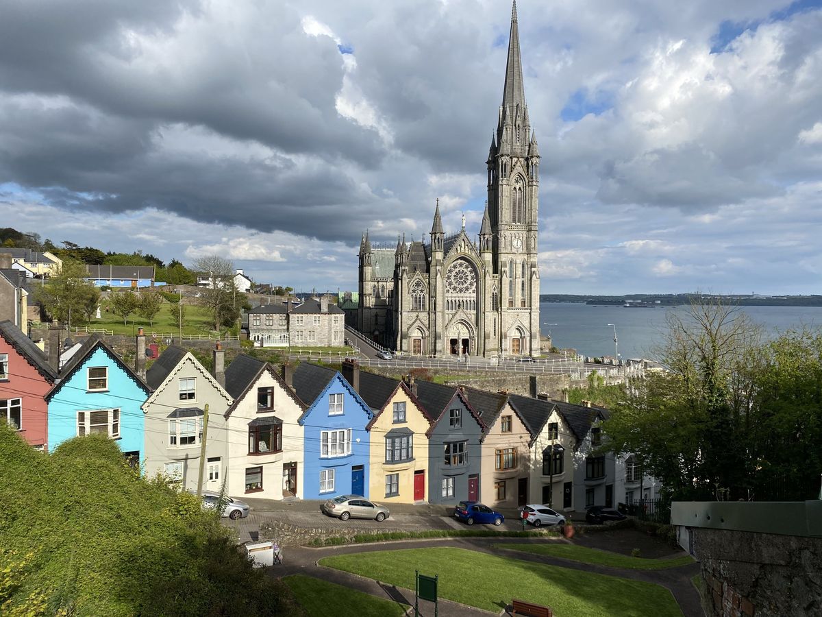 Barevná řada domků v&nbsp;přístavním městě Cobh doplňuje majestátní katedrálu svatého Kolmana, s&nbsp;výhledem na mořský záliv.