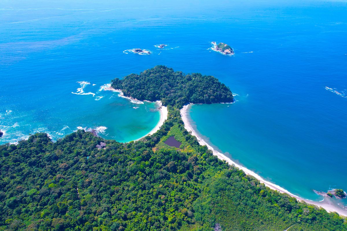 Pohled z&nbsp;výšky na národní park Manuel Antonio v&nbsp;Kostarice s&nbsp;hustým tropickým lesem a&nbsp;malebnými plážemi obklopenými Tichým oceánem.