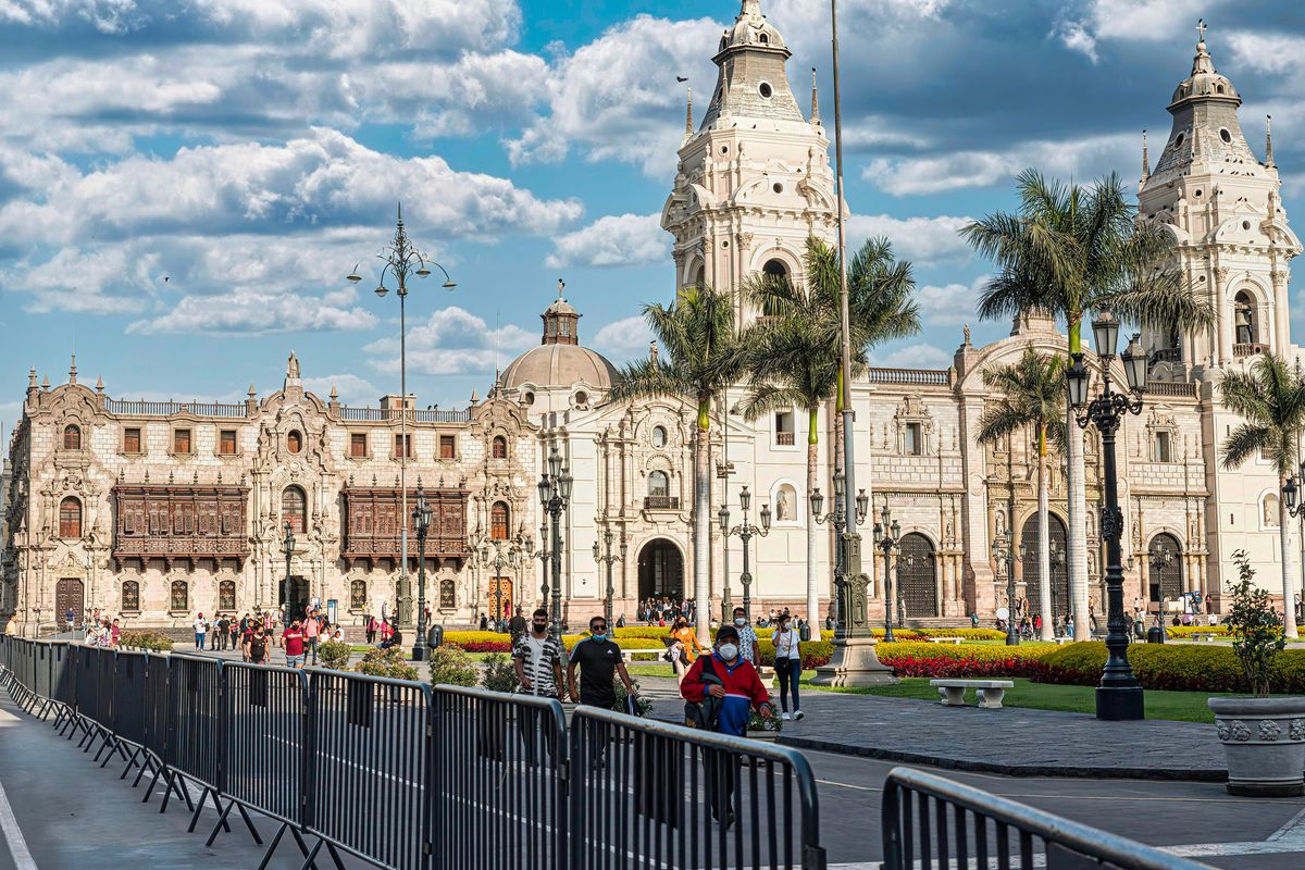Koloniální architektura Katedrály v Limě a nádvoří zdobené palmami s modrým nebem na pozadí.