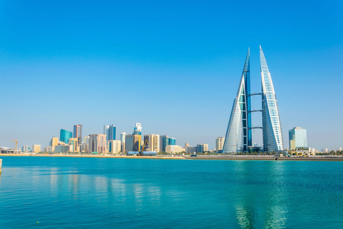 Panoráma města Manáma s ikonickou budovou Bahrain World Trade Center u klidného moře.
