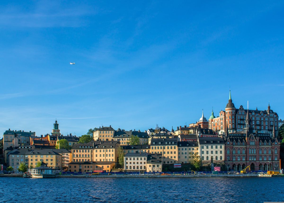 Historické budovy čtvrti Södermalm ve Stockholmu se odrážejí ve vodách místního jezera pod jasně modrou oblohou.