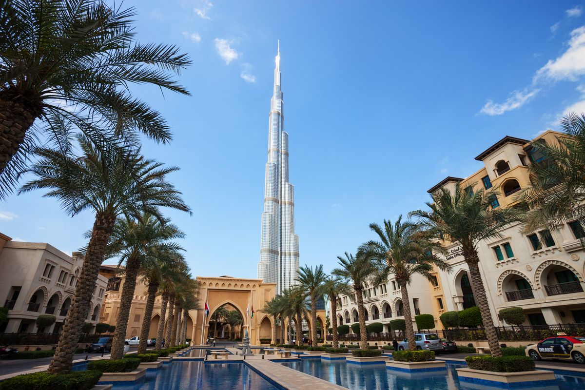 Burj Khalifa, nejvyšší budova světa, se vypíná do nebe obklopená palmovým rostlinstvem v Dubaji.