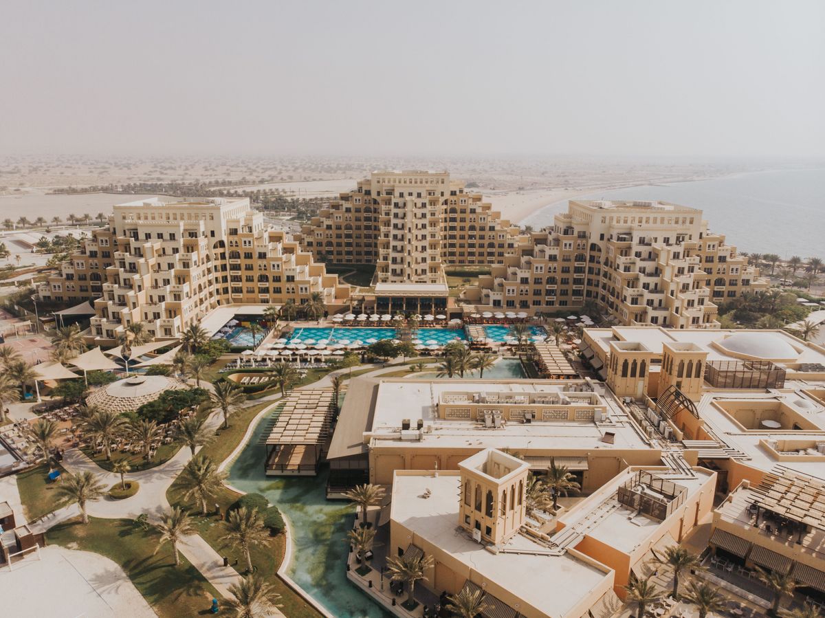 Luxusní resort v Ras al-Khaimah ve Spojených arabských emirátech, obklopený palmami a s výhledem na pláž a moře.
