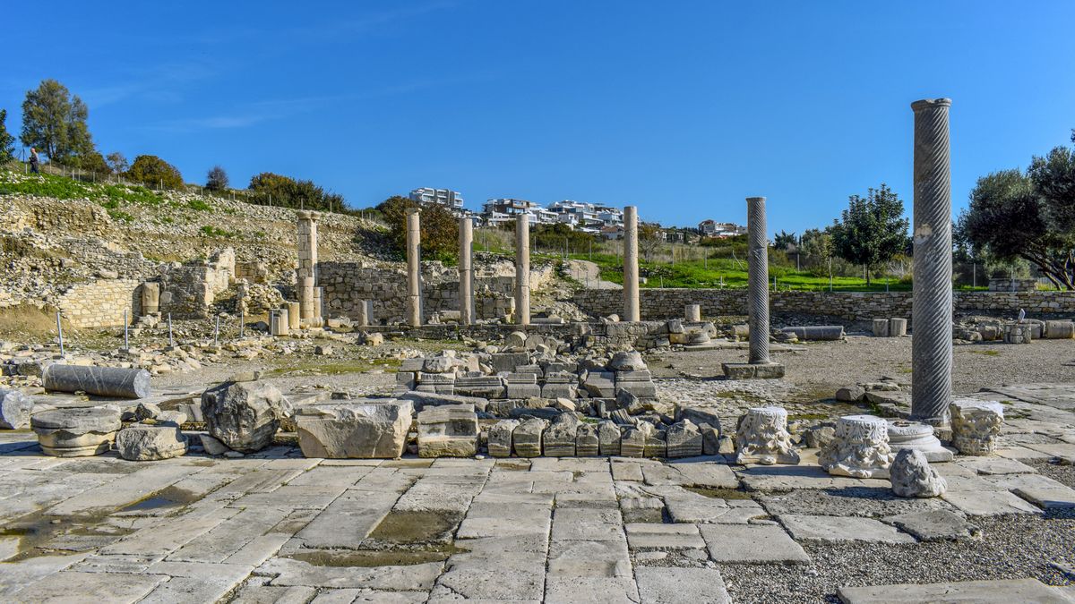 Pozůstatky antického města Amathus zahrnující sloupy a rozpadající se kamenné zdi na pozadí moderní výstavby. Amathús se nachází poblíž pobřeží Limassolu na Kypru.