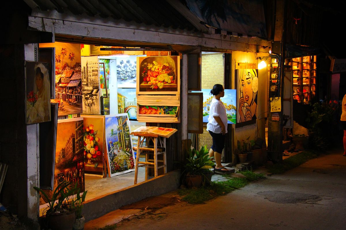Ulice na ostrově Ko Samui v Thajsku s galerií plnou pestrých obrazů vyzařujících uměleckou atmosféru.