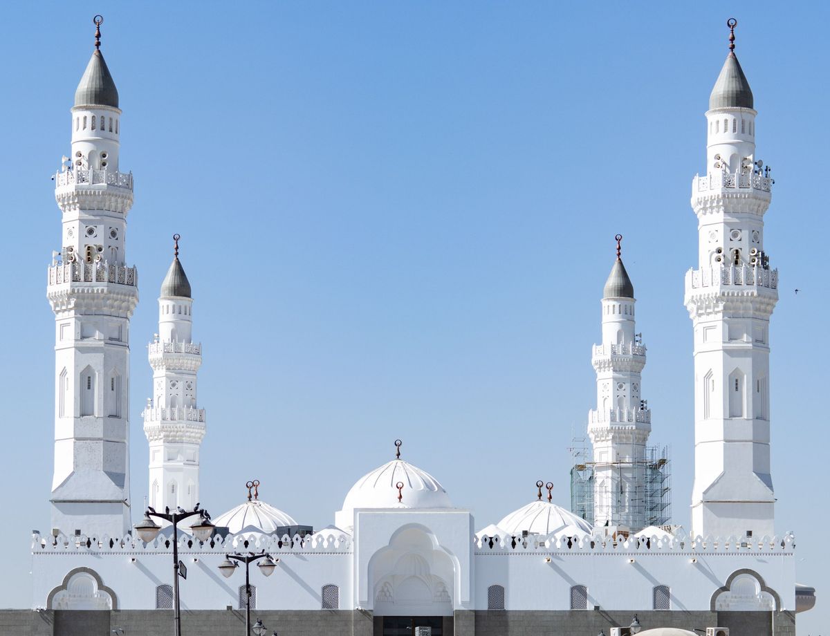 Bílá mešita se čtyřmi minarety v Medíně, Saúdská Arábie, vystupuje proti jasně modré obloze.