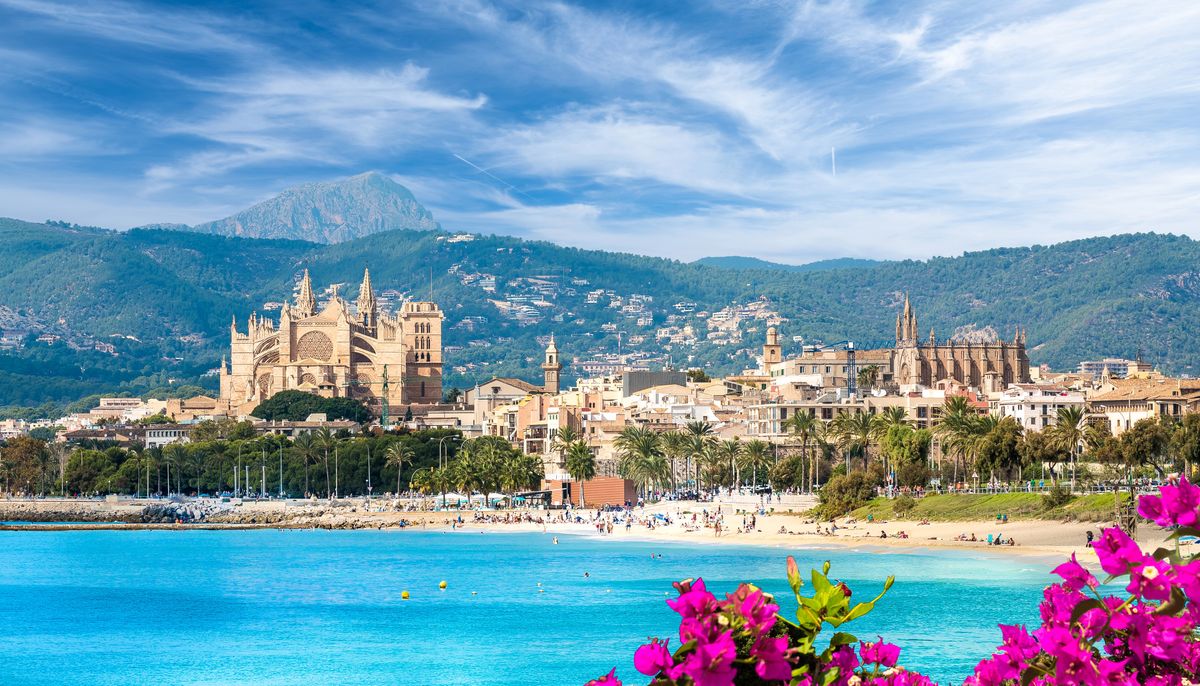 Katedrála La Seu se tyčí nad historickým centrem města Palma de Mallorca, okolo ní se rozkládá pobřeží a pláže s modrým mořem.